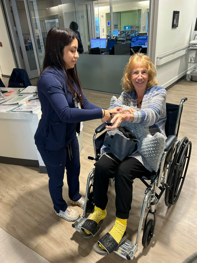 Antonina Duridanova smile in a wheelchair as a nurse adjusts a bandage on her arm.