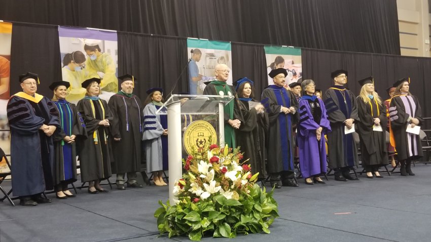 President William L. Henrich, M.D., MACP, stands at a podium at the School of Health Professions and School of Nursing joint commencement ceremony