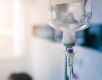 Close up of medical drip or IV drip chamber in patient room.
