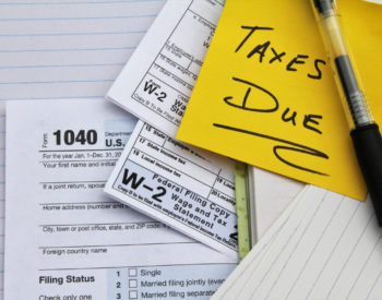 Tax return forms and wage statements with a note saying Taxes Due. An IRS tax return form 1040 and two W-2 Wage and Tax Statement forms indicating wages were earned from two employers.