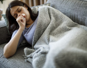 Woman sick on couch with cough.