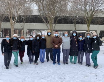 Members of family and community medicine stand in the snow on campus.