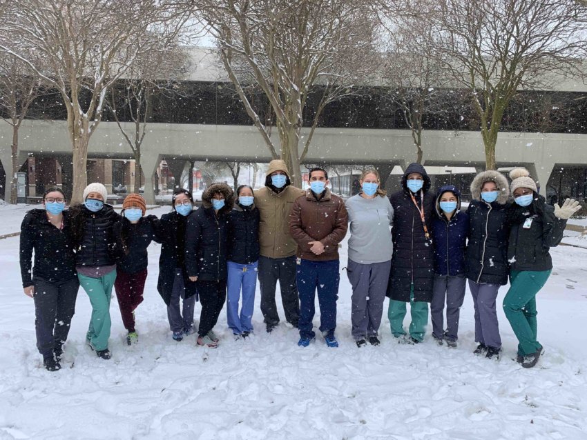 Members of family and community medicine stand in the snow on campus.