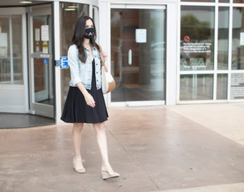 woman walks at UT Health San Antonio wearing a mask.
