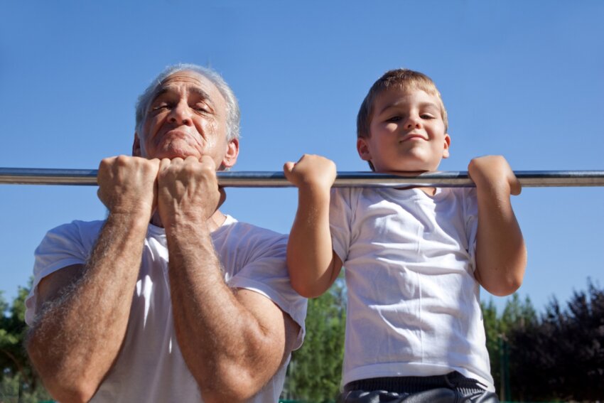 Photo of grandpa and grandson doing chin-ups side by side.