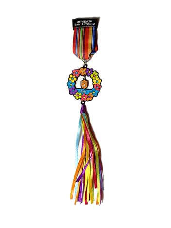 The UT Health San Antonio 2022 Fiesta medal, featuring a colorful flower crown with flowing ribbons.