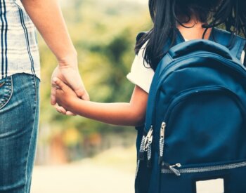 Photo of Child with Backpack Holding Mom's Hand
