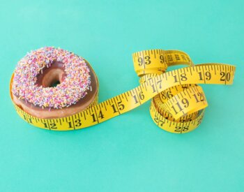 An image of obesity-overweight: A donut with a waist tape