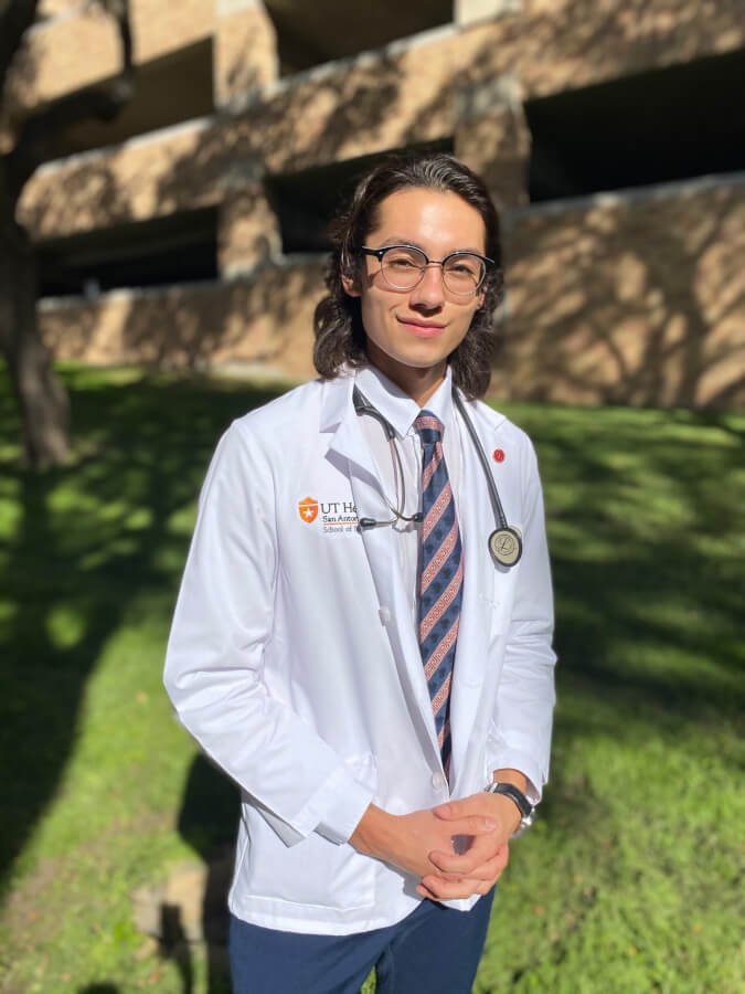 School of Nursing student stands wearing his white coat and stethoscope.