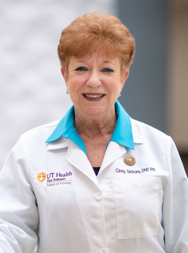 Dr. Cindy Sickora in her UT Health San Antonio-branded white coat.