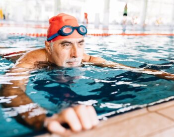 Photo of older man in a pool with a swimmer's cap and goggles