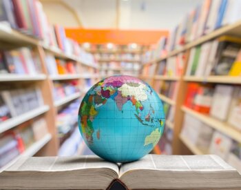 A globe of the Earth sits on an open textbook.