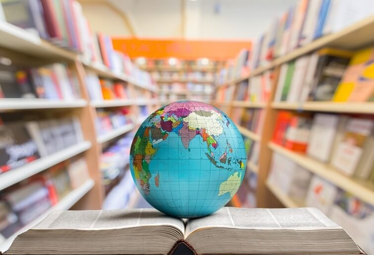 A globe of the Earth sits on an open textbook.