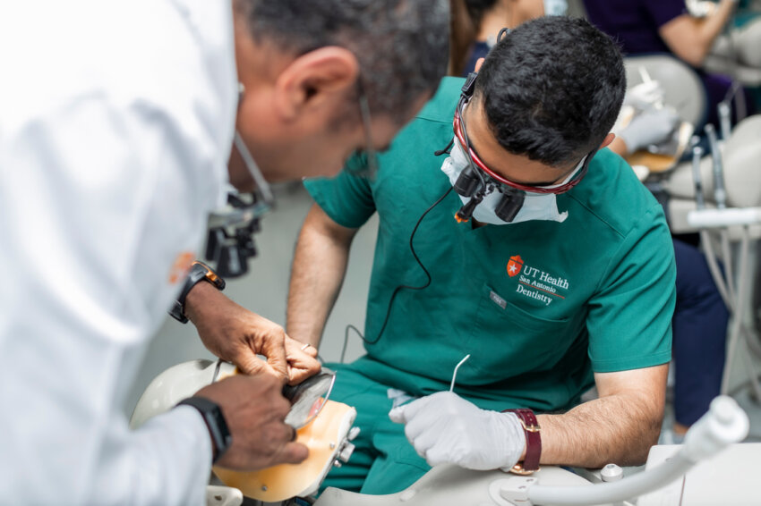 A dental faculty member guides a dental student with a procedure conducted on a manikin.