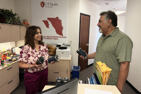 Two employees discuss the design of promotional cups.