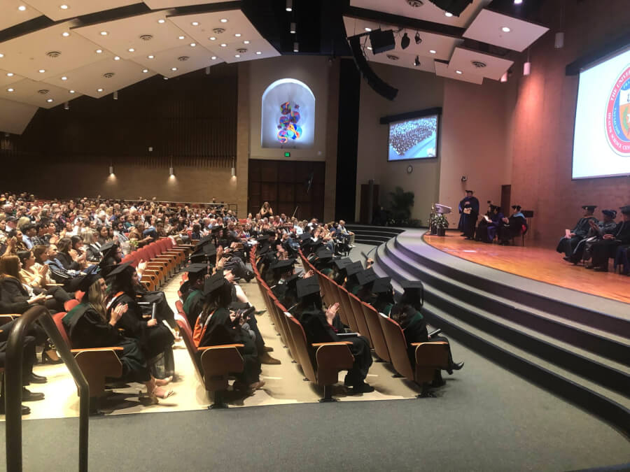 Wide shot of the Holly Auditorium filled with graduates and their families.