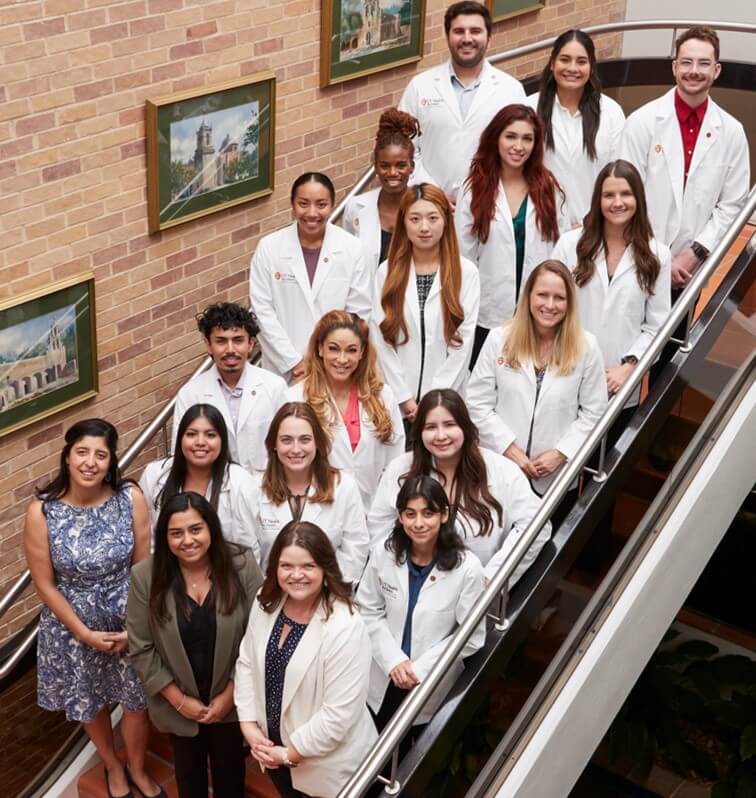 Program participants take a group photo standing on a staircase in the School of Nursing.