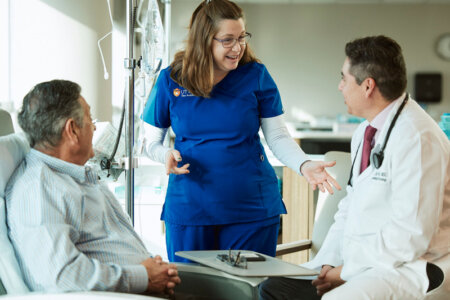 A nurse and doctor talk to a patient at the Mays Cancer Center.