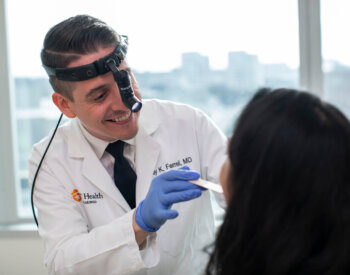 Dr. Ferrell examines a patient's mouth using a tongue depressor.