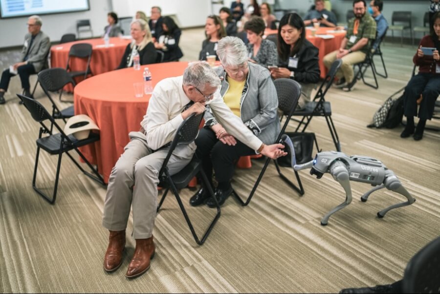 An event attendee stretches his hand out while the robot dog lifts its paw to shake.