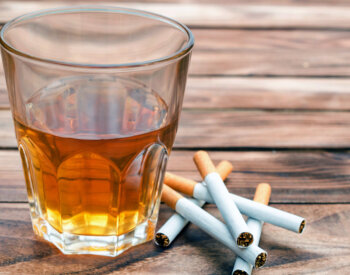 a stock photo of a glass of alcohol and a stack of cigarettes.