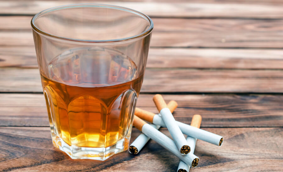 a stock photo of a glass of alcohol and a stack of cigarettes. 
