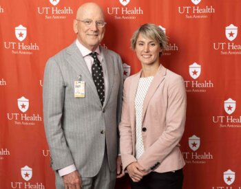 Gina Baxter, 2024 graduate of the Master of Science in Speech-Language Pathology program, poses with former UT Health San Antonio President William L. Henrich, MD, MACP