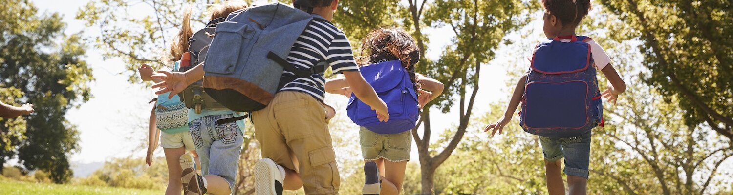 Five school kids running in a field, back view, close up