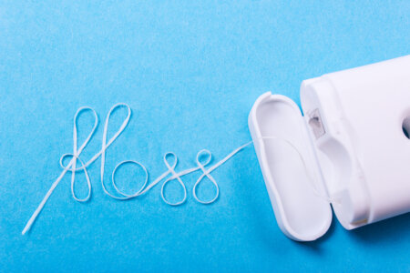 The word floss is spelled out using string floss on top of a blue background.
