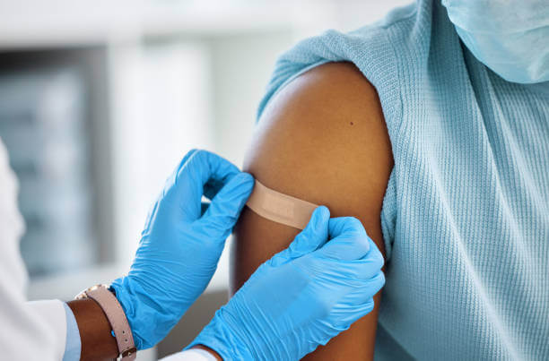 A health provider with gloves places a bandage on a patient's arm.