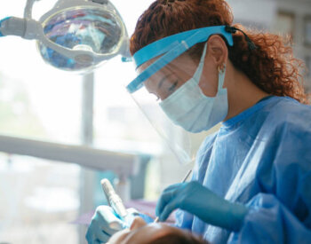 Dental provider working on a patient in full personal protective equipment.
