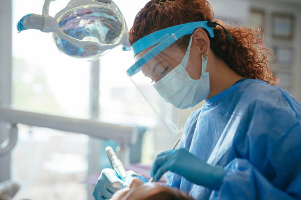 Dental provider working on a patient in full personal protective equipment.