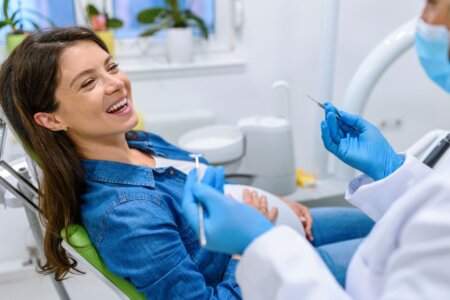 Pregnant patient smiles at dentist while in the dental chair.
