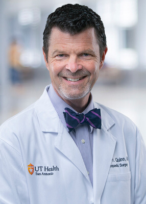 A professional head and shoulders photo of Dr. Robert Quinn in his white coat.