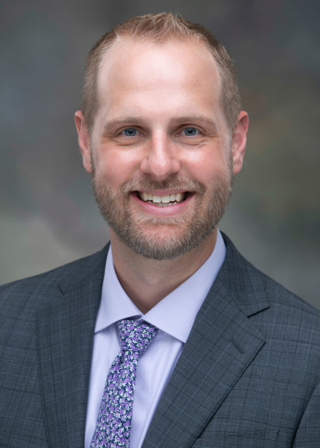 A professional head and shoulders photo of Dr. Ryan Rose in a suit and tie.