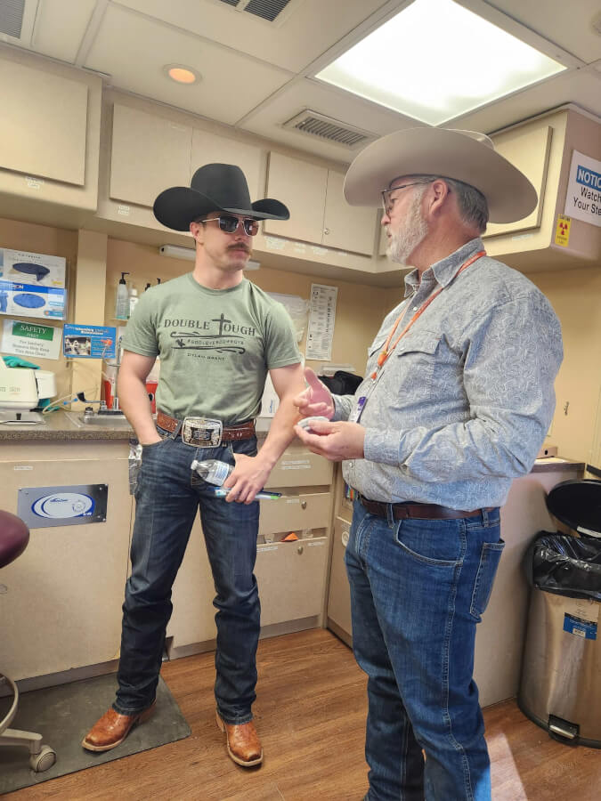 Donnie and Dr. Stafford, donnine cowboy hats, discuss mouthgaurds in the mobile clinic.
