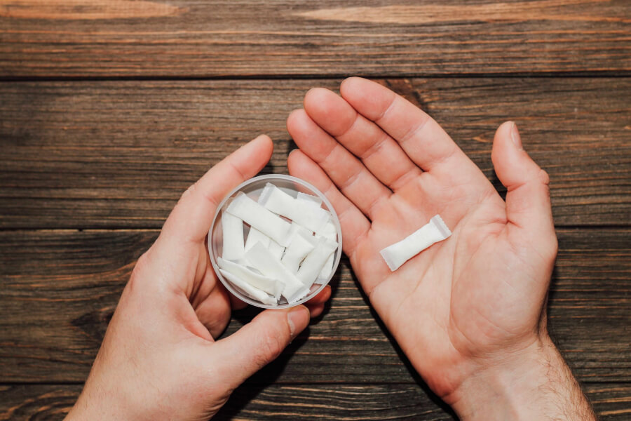 Male hands hold a box of nicotine pouches.