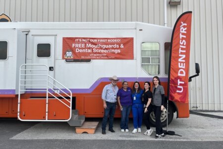 Volunteers from the School of Dentistry stand for a photo in front of the mobile dental clinic.