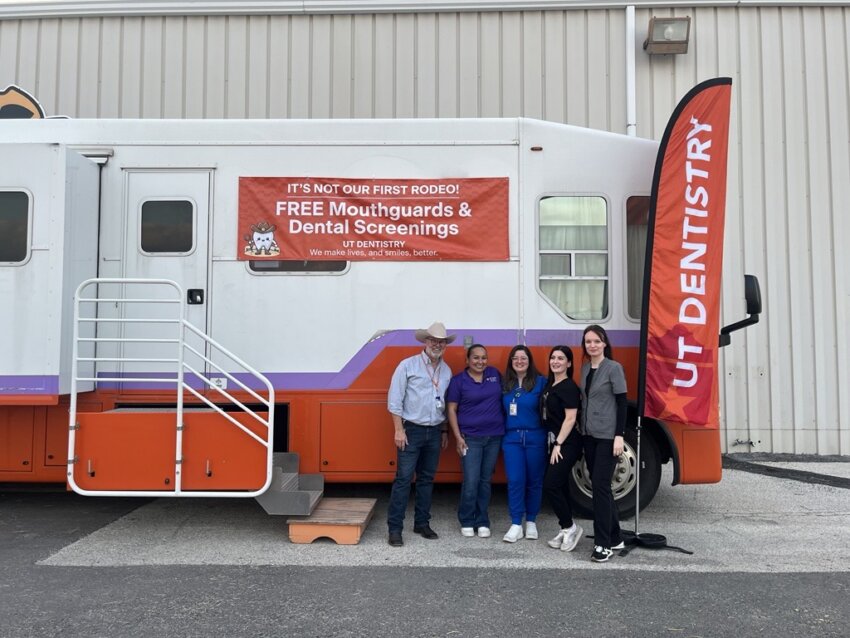 Volunteers from the School of Dentistry stand for a photo in front of the mobile dental clinic.