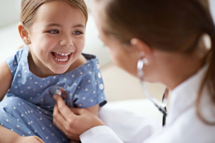 Happy child, girl and stethoscope of health provider for medical consulting, healthy lungs and listening to heartbeat. Face of laughing kid, pediatrician and chest assessment for healthcare analysis in clinic.