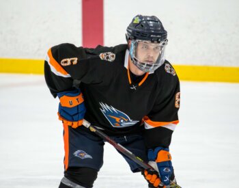 Jordan Nolan on the ice in his UTSA Hockey gear in the ready stance with his hockey stick in hand.