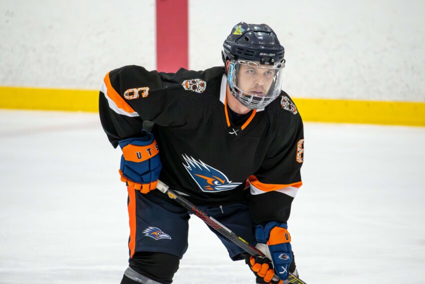 Jordan Nolan on the ice in his UTSA Hockey gear in the ready stance with his hockey stick in hand.