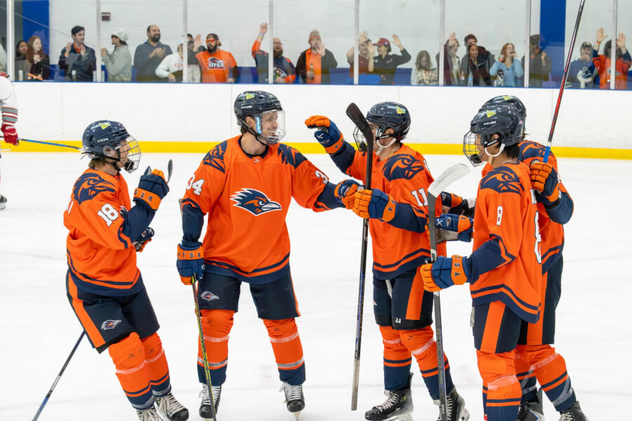 UTSA Hockey players in uniform gather on the ice.