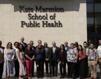 faculty and students stand in front of the Kate Marmion School of Public Health name.