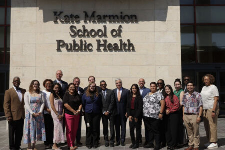 faculty and students stand in front of the Kate Marmion School of Public Health name.