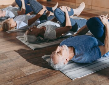 group of senior people stretching in yoga mats in studio
