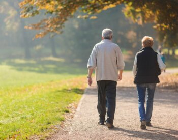 Senior citizen couple taking a walk in a park during autumn morning.