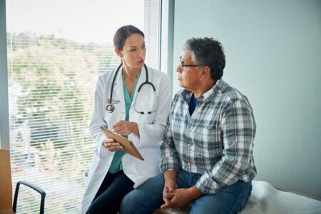 A female physician talks to a patient sitting on an examination table in a clinic.