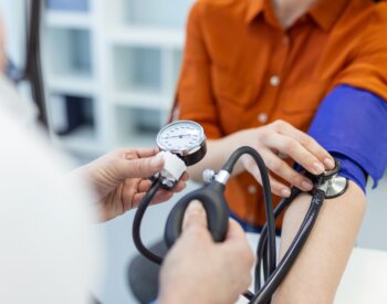 Doctor using sphygmomanometer with stethoscope checking blood pressure to a patient in the hospital.
