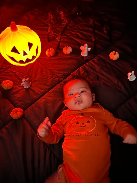 Baby Jeremiah lays next to a glowing jack-o'-lantern at three months old.